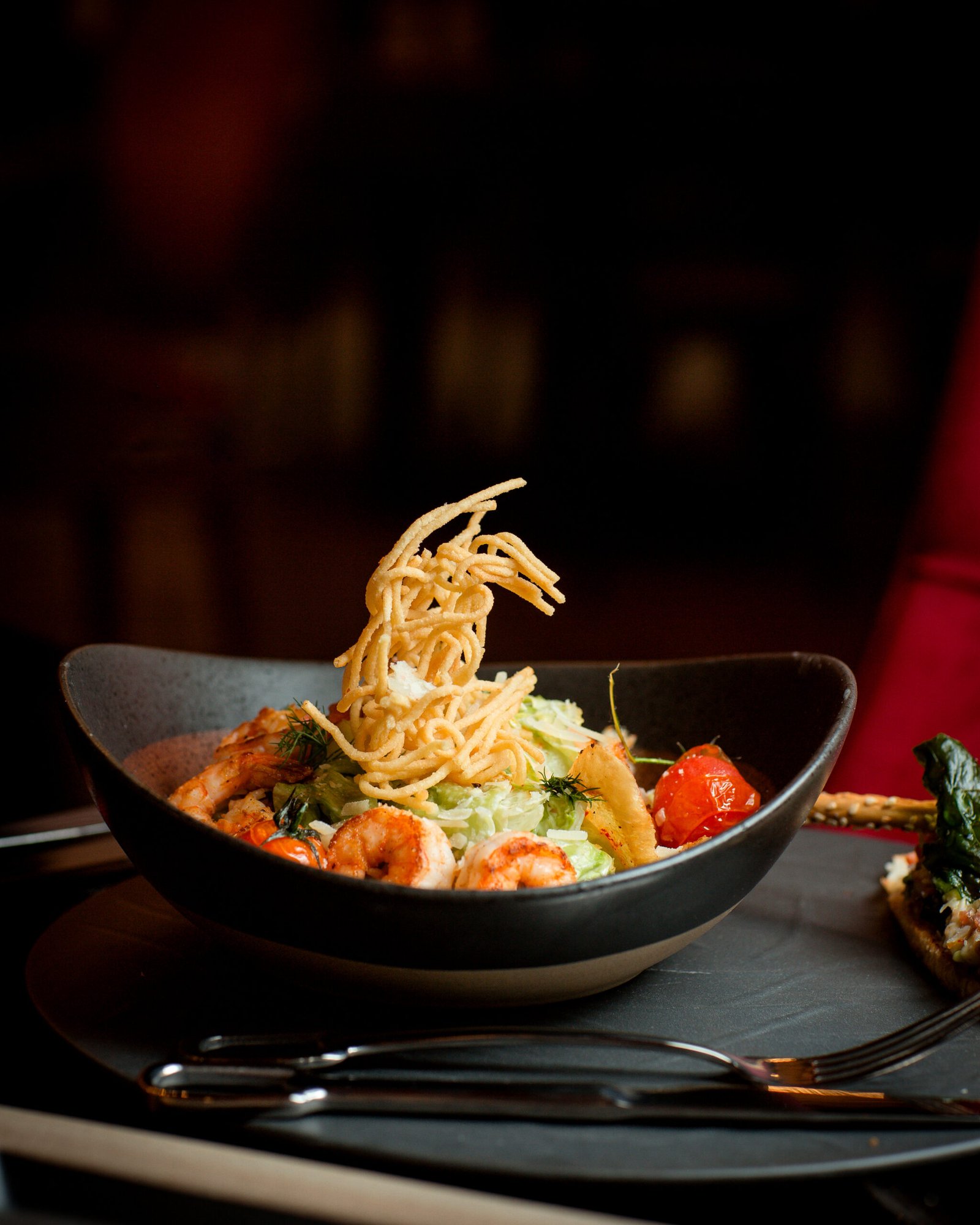 About side view of shrimp caesar plate topped with potato shoestrings